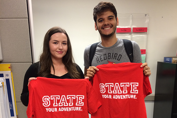 two students holding STATE your adventure shirts